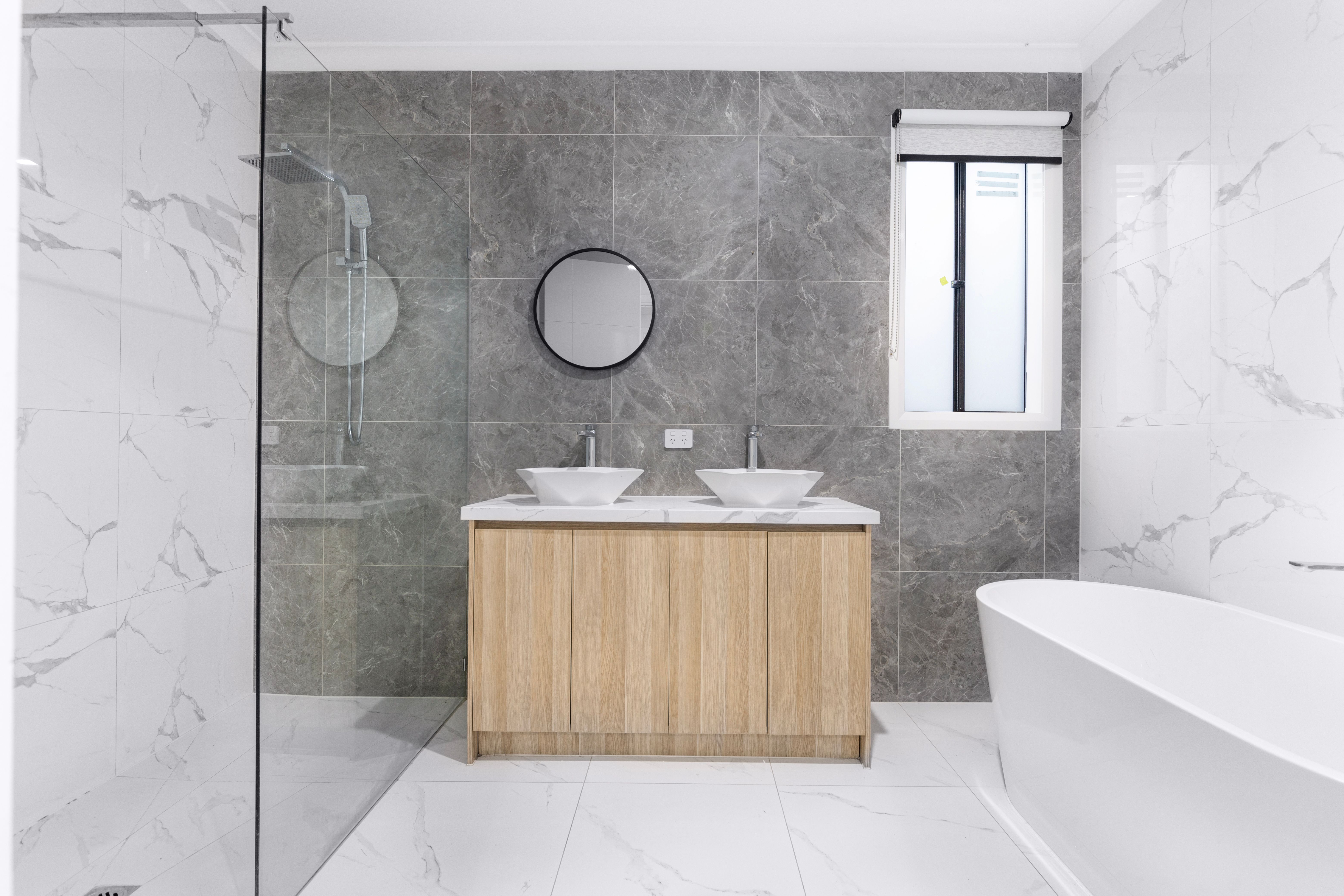Modern bathroom with walk-in shower, double vanity, and tile finishes